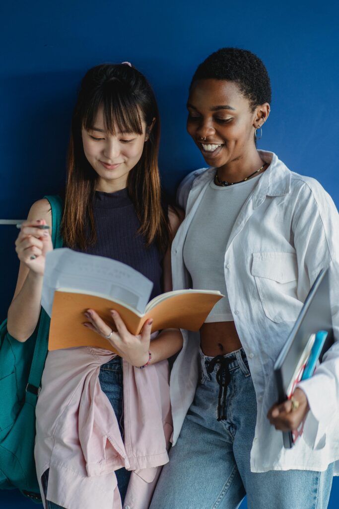 Multiethnic classmates standing with notebooks near wall