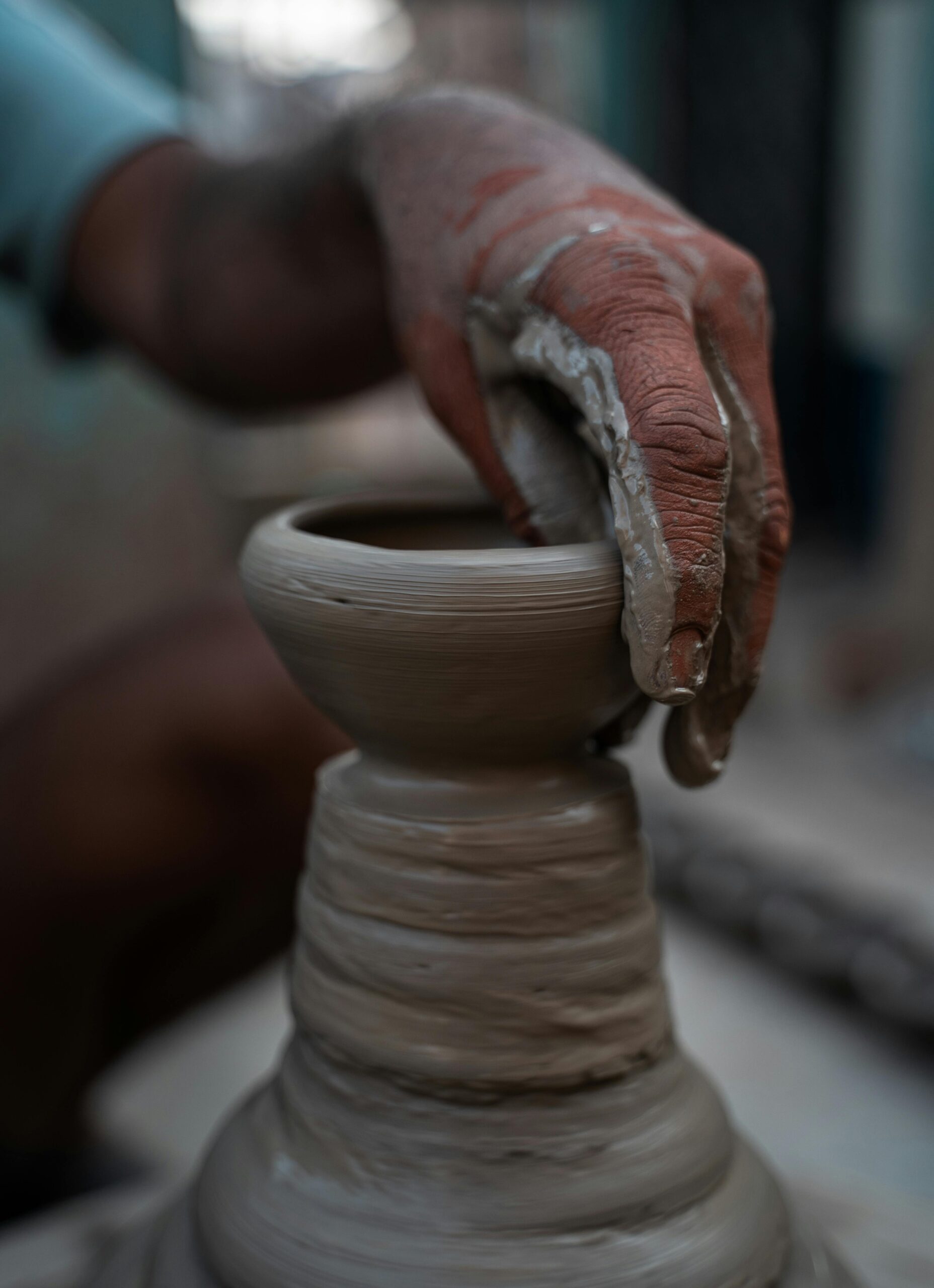 A skilled artisan shapes a clay pot on a potter's wheel, highlighting traditional craftsmanship.